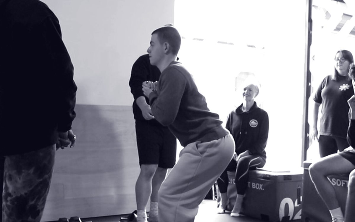 A student practising a squat while a tutor coaches at Edinburgh PT Academy